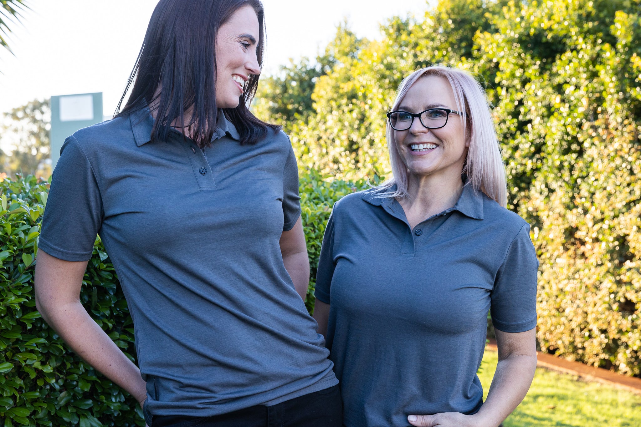 Two women smiling in gray polo shirts