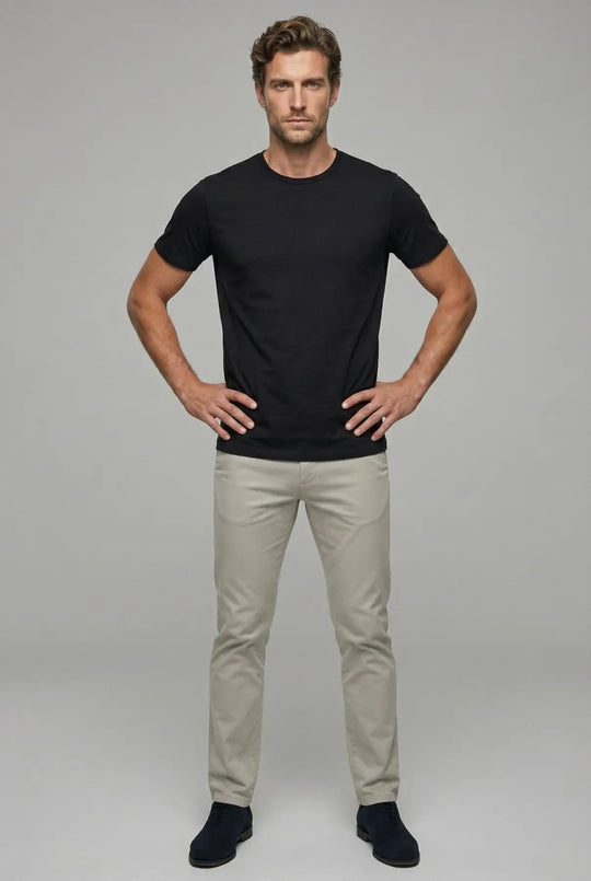 Man wearing a black t-shirt and beige pants against a gray background