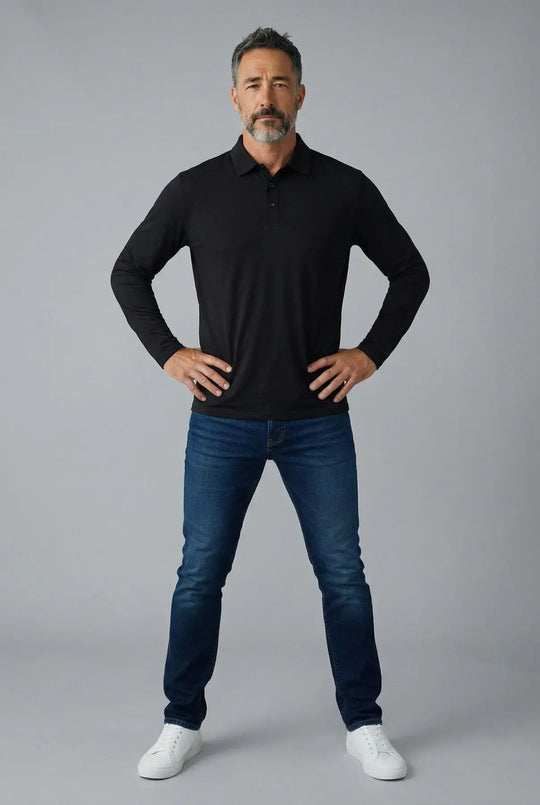 Man wearing a black long-sleeve shirt and blue jeans against a gray background