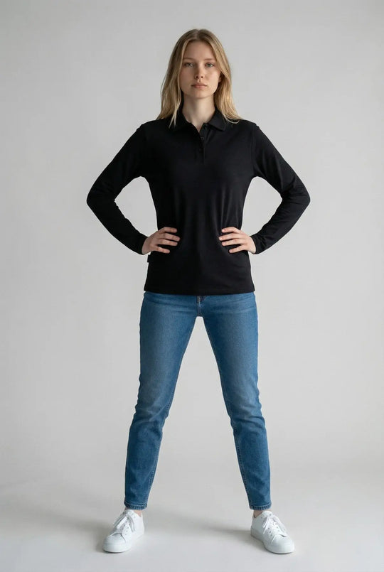 Woman wearing a black long-sleeve shirt and blue jeans on a gray background