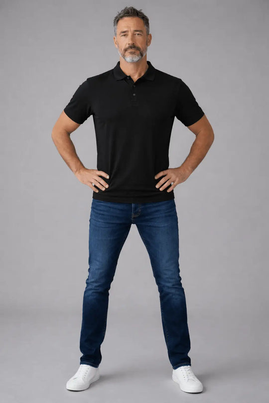 Man wearing a black polo shirt and blue jeans on a gray background