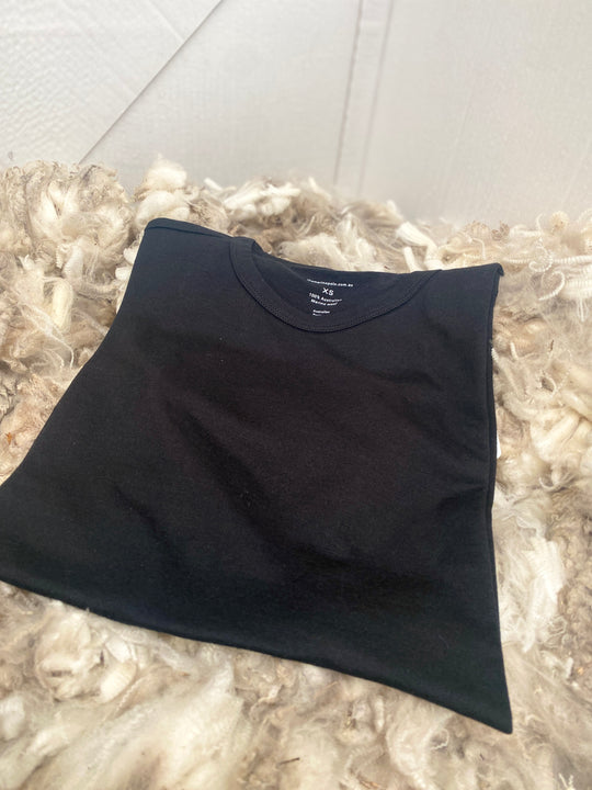 Folded black t-shirt on a textured surface with a light-colored wall background