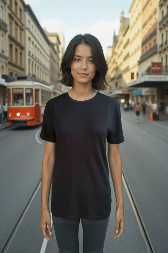 Woman standing wearing black merino T-shirt on a city street with a blurred background