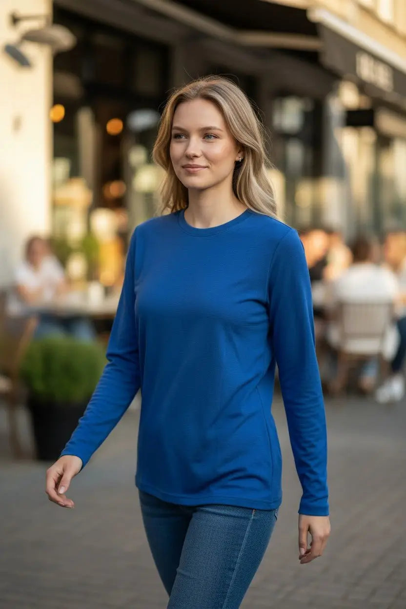 Woman wearing a blue long-sleeve shirt walking on a street.