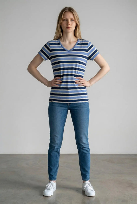 Woman wearing a blue and white striped shirt and jeans standing against a plain background