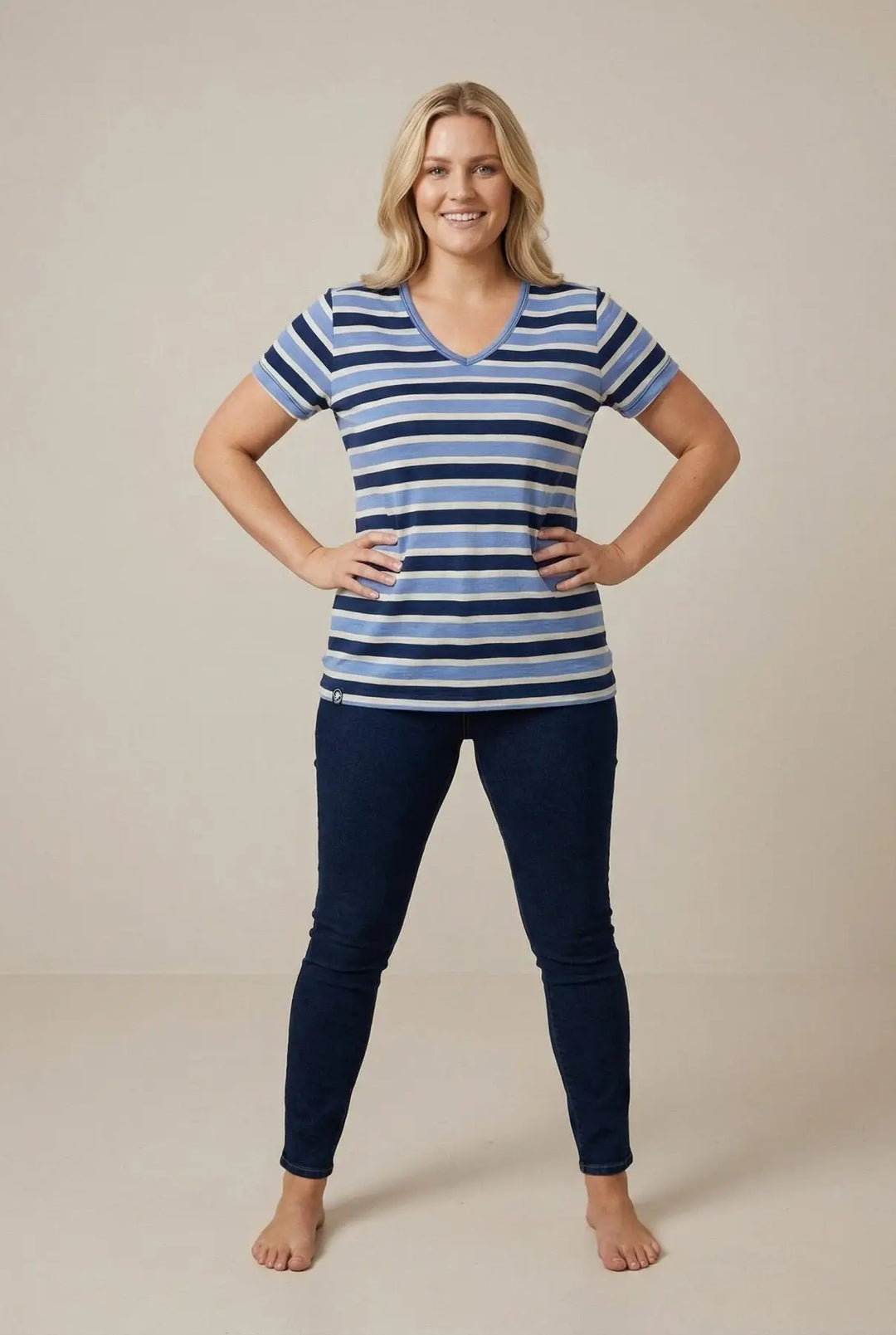 Woman wearing a blue and white striped shirt and dark blue pants on a beige background