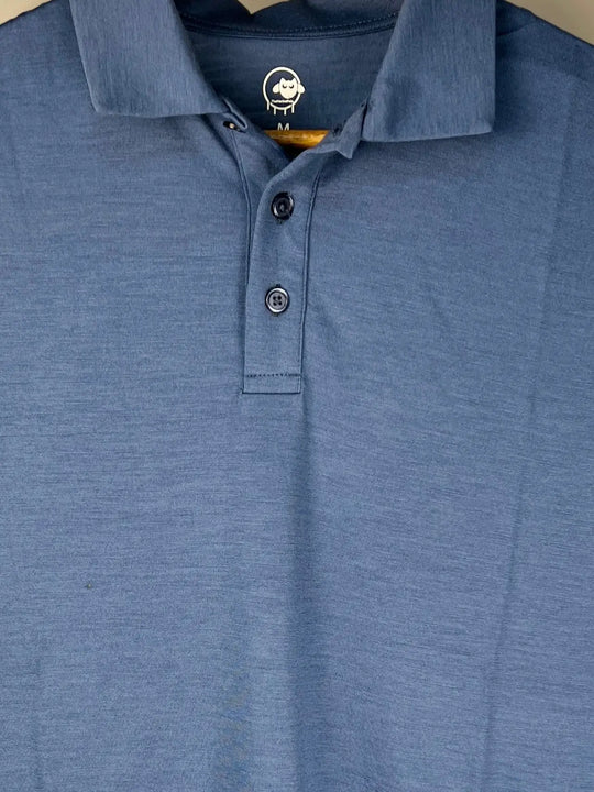 Blue polo shirt with a brand logo on the collar against a beige background