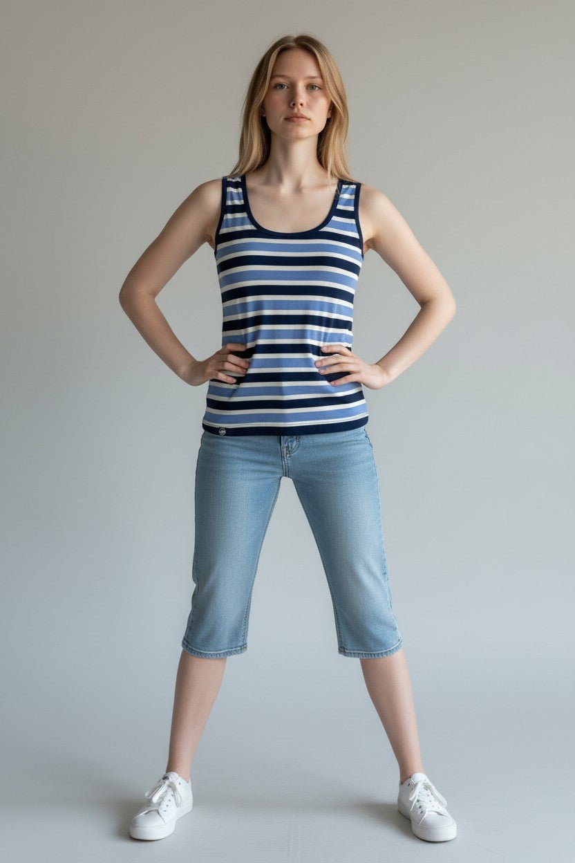Woman wearing a striped tank top and light blue jeans against a plain background