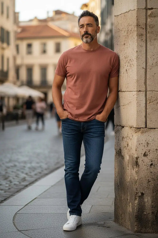 Man leaning against a stone wall on a street with blurred background