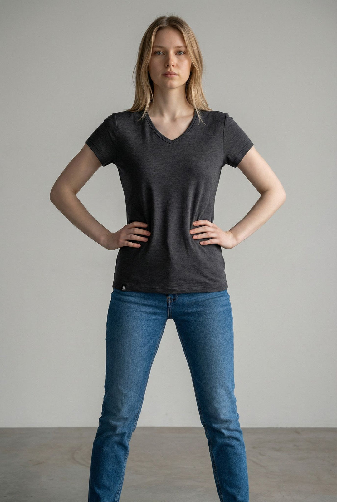 Woman wearing a black t-shirt and blue jeans against a plain background