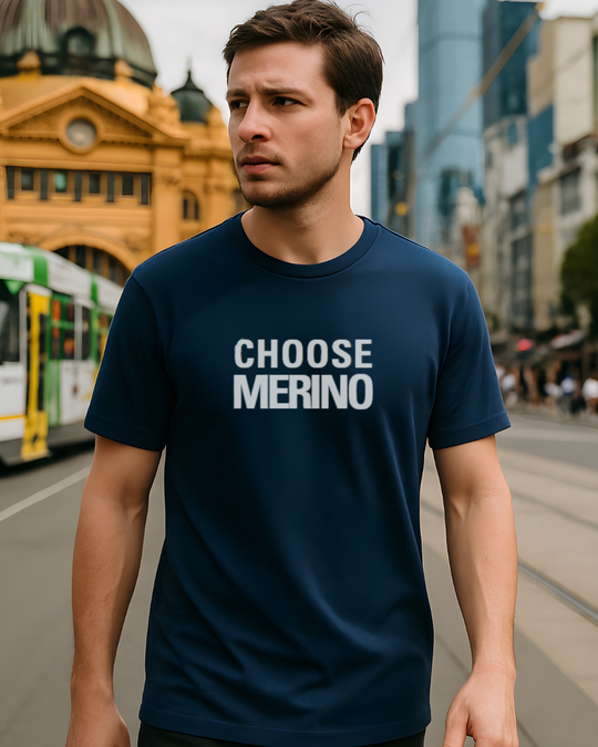 Man wearing a navy blue t-shirt with 'CHOOSE MERINO' text on a city street.