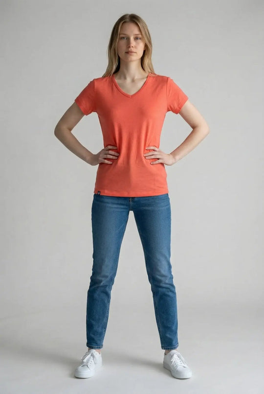 Woman wearing an orange t-shirt and blue jeans on a plain background
