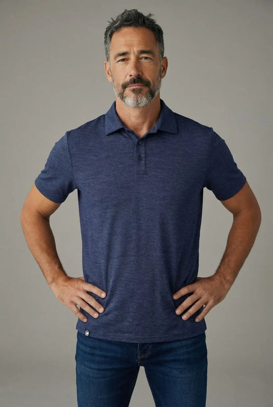 Man wearing a blue polo shirt and jeans against a gray background