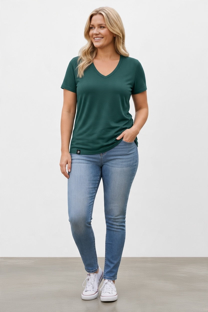woman in green merino wool t-shirt blue jeans and white shoes