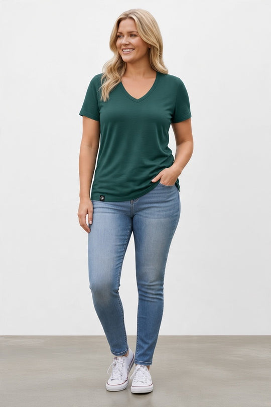woman in green merino wool t-shirt blue jeans and white shoes