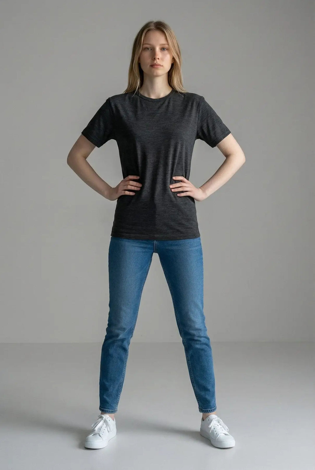 Person wearing a black t-shirt and blue jeans on a gray background