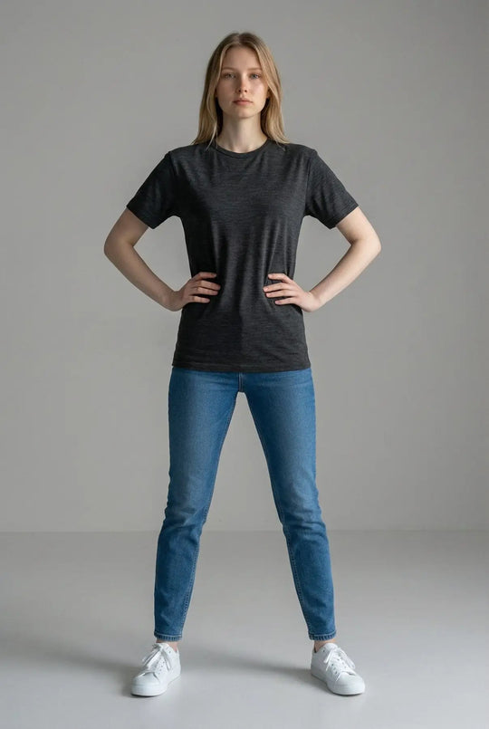 Person wearing a black t-shirt and blue jeans on a gray background