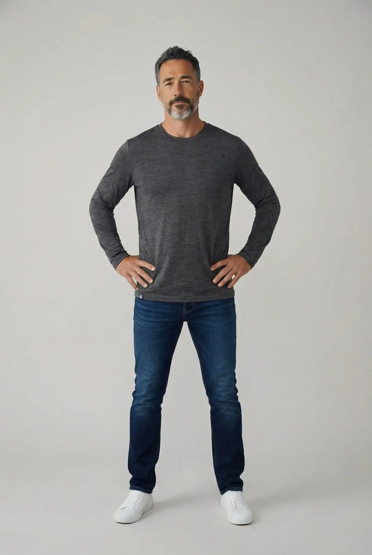 Man wearing a dark gray long-sleeve shirt and blue jeans on a light gray background