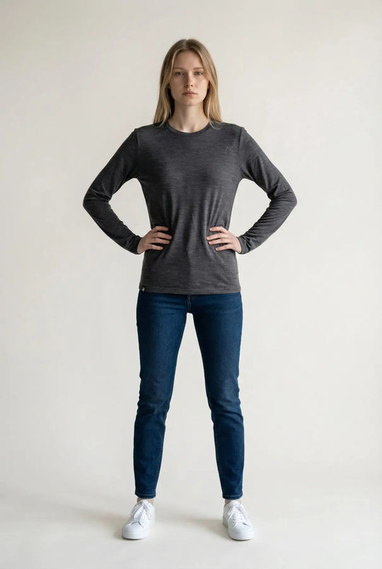 Woman wearing a dark gray long-sleeve shirt and blue jeans on a white background