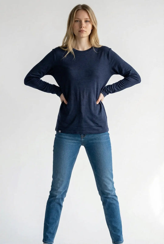 Woman wearing a navy long-sleeve shirt and blue jeans on a white background
