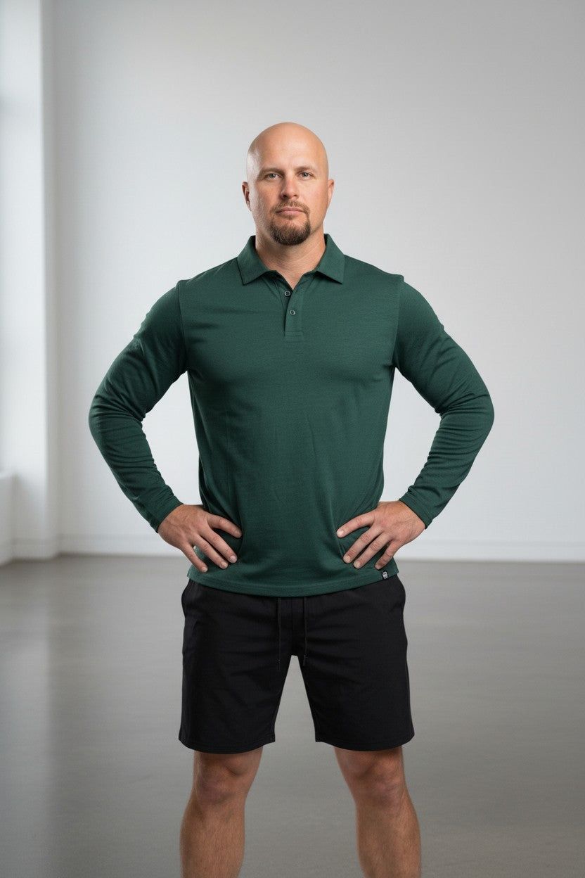 Man wearing a green long-sleeve polo shirt and black shorts against a plain background