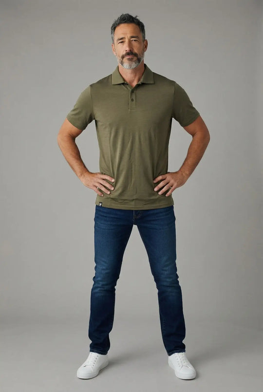 Man wearing a green polo shirt and blue jeans against a gray background