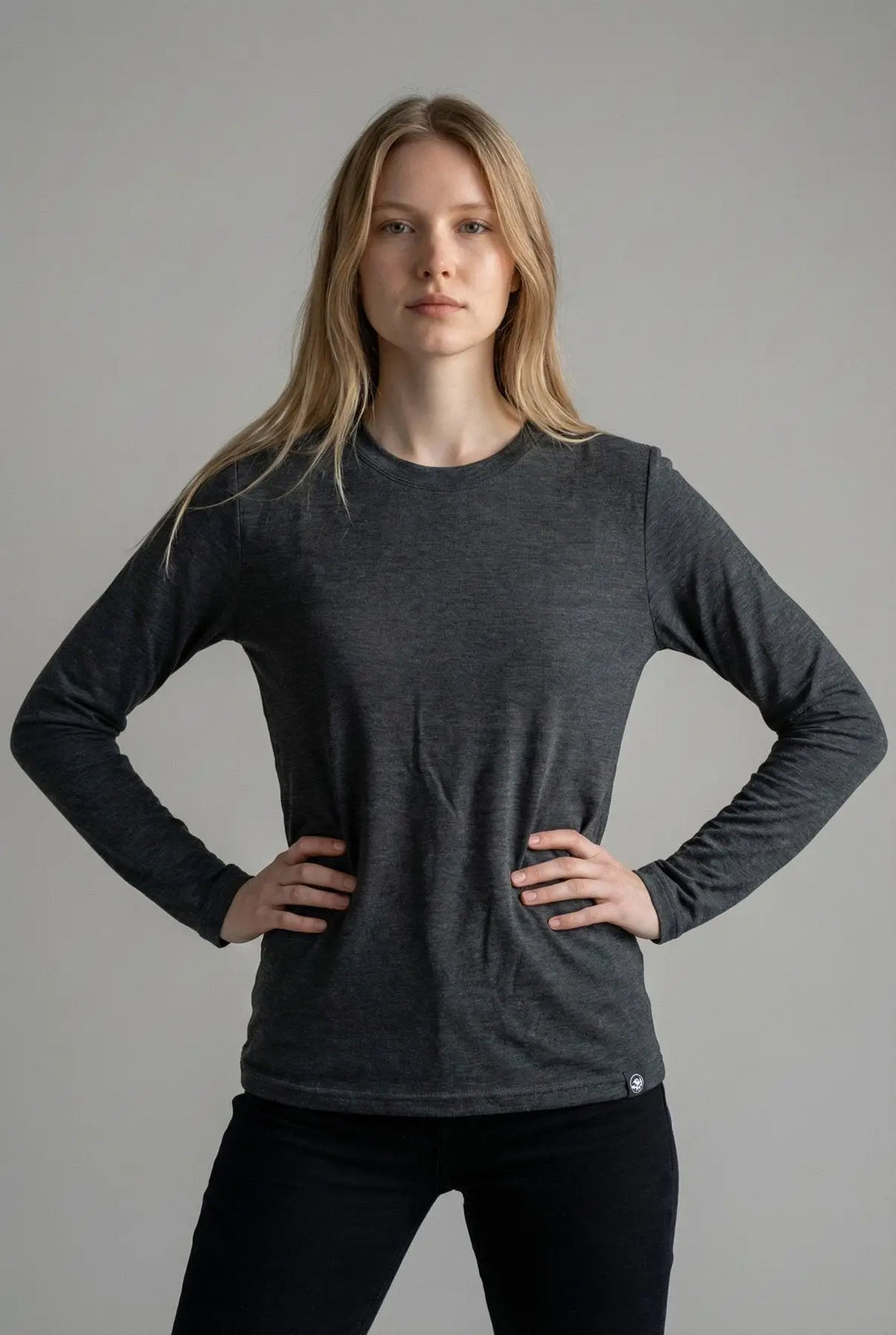 Woman wearing a dark gray long-sleeve shirt against a plain background
