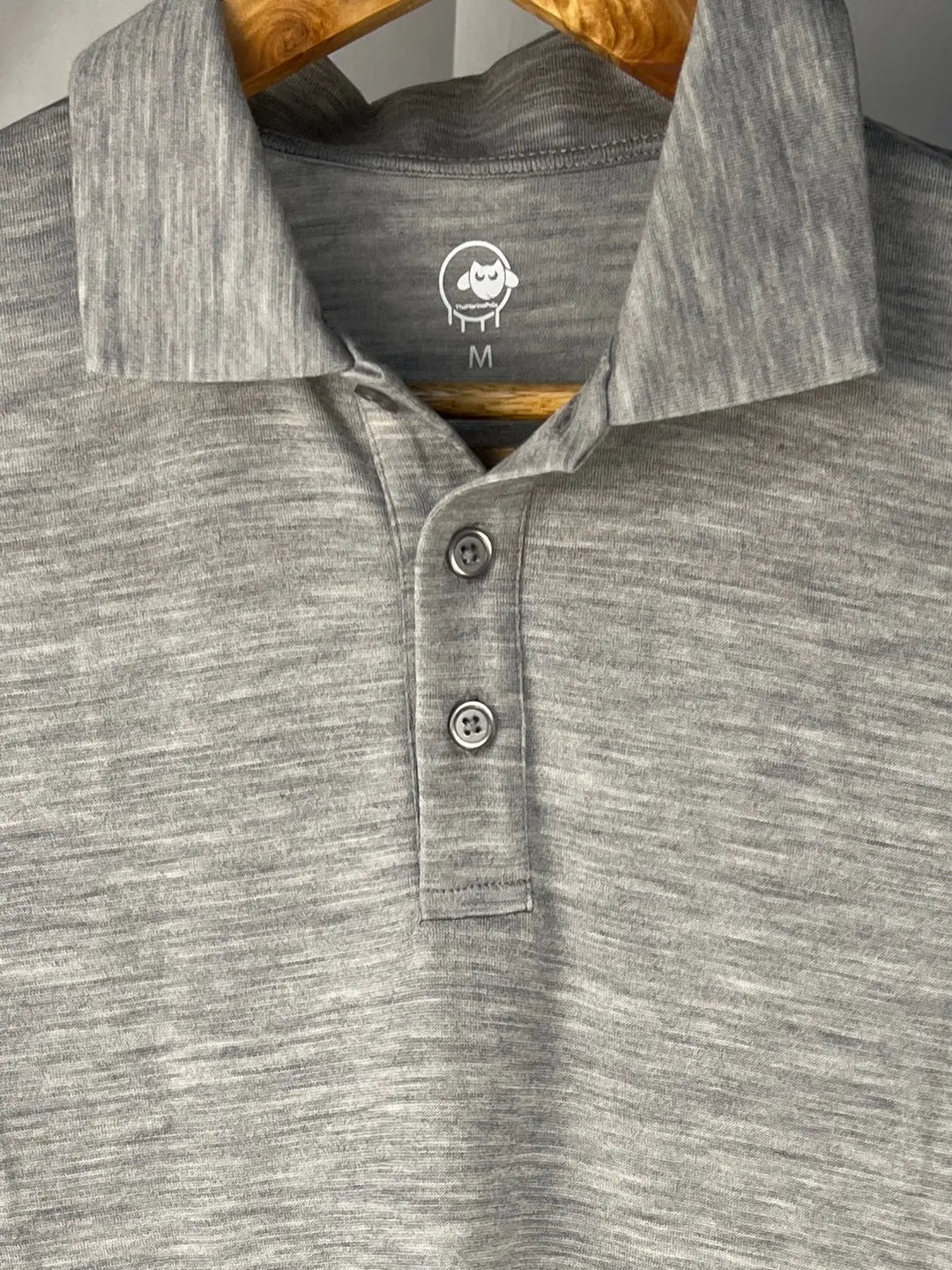 Gray polo shirt with a brand logo on a hanger