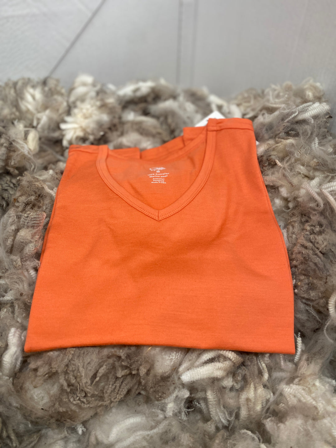 Orange V-neck shirt on a textured gray surface