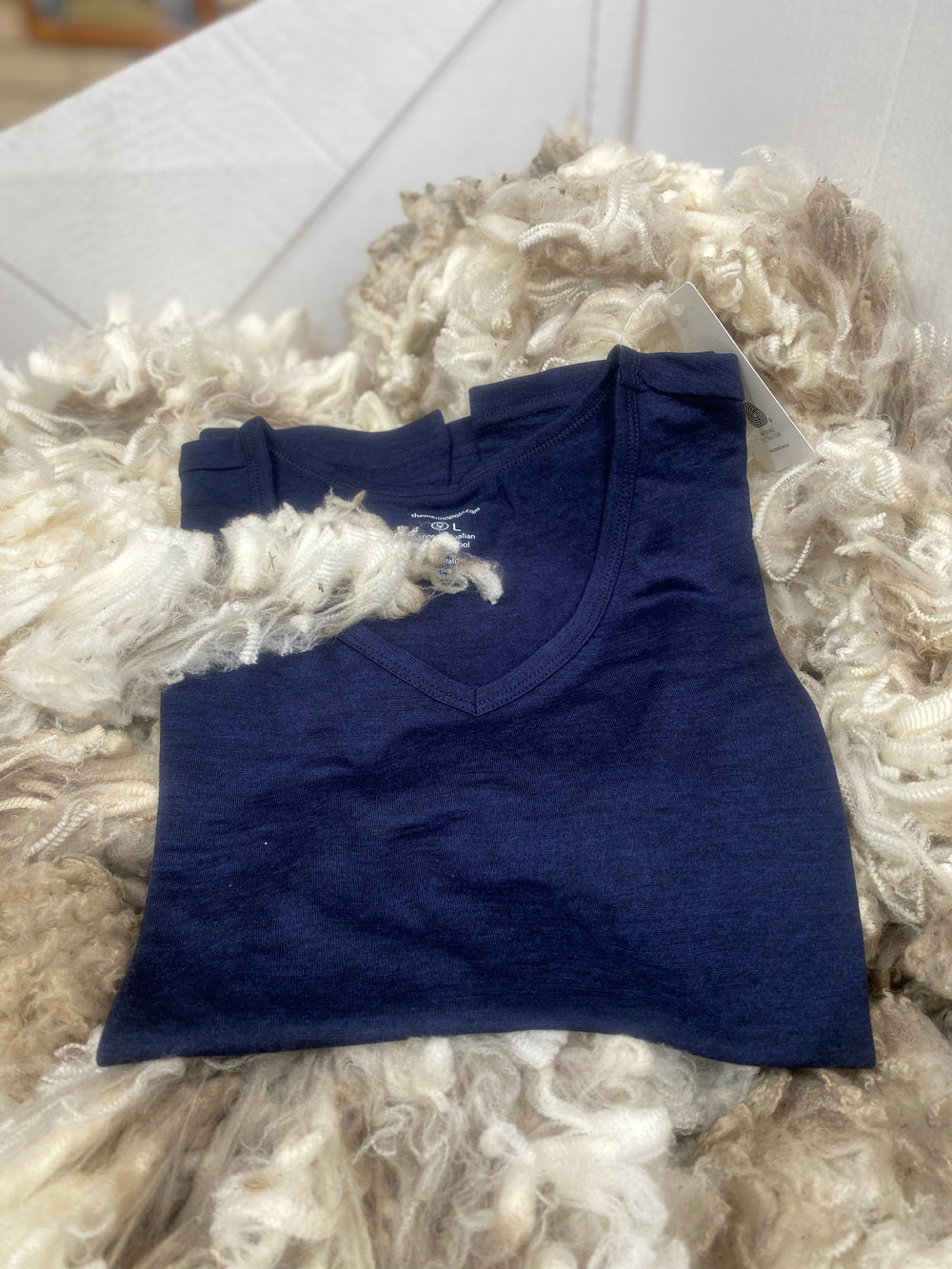 Folded merino blue t-shirt on a textured white surface