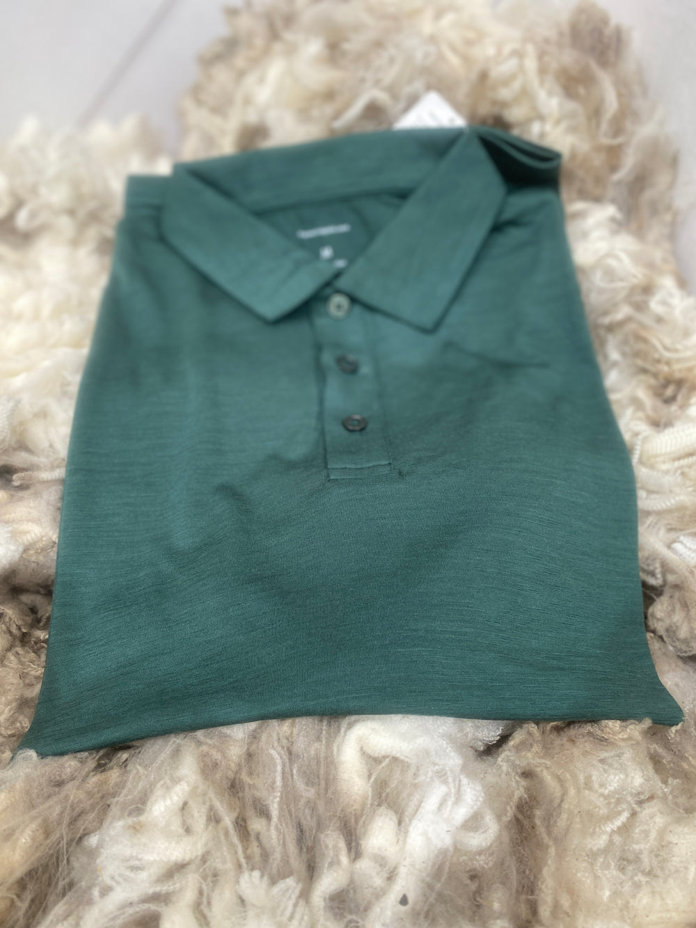 Folded green polo shirt on a textured surface