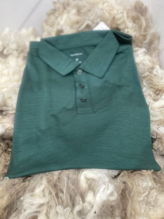 Folded green polo shirt on a textured surface