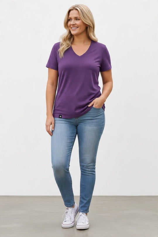A pregnant woman wearing a purple merino wool T-shirt.