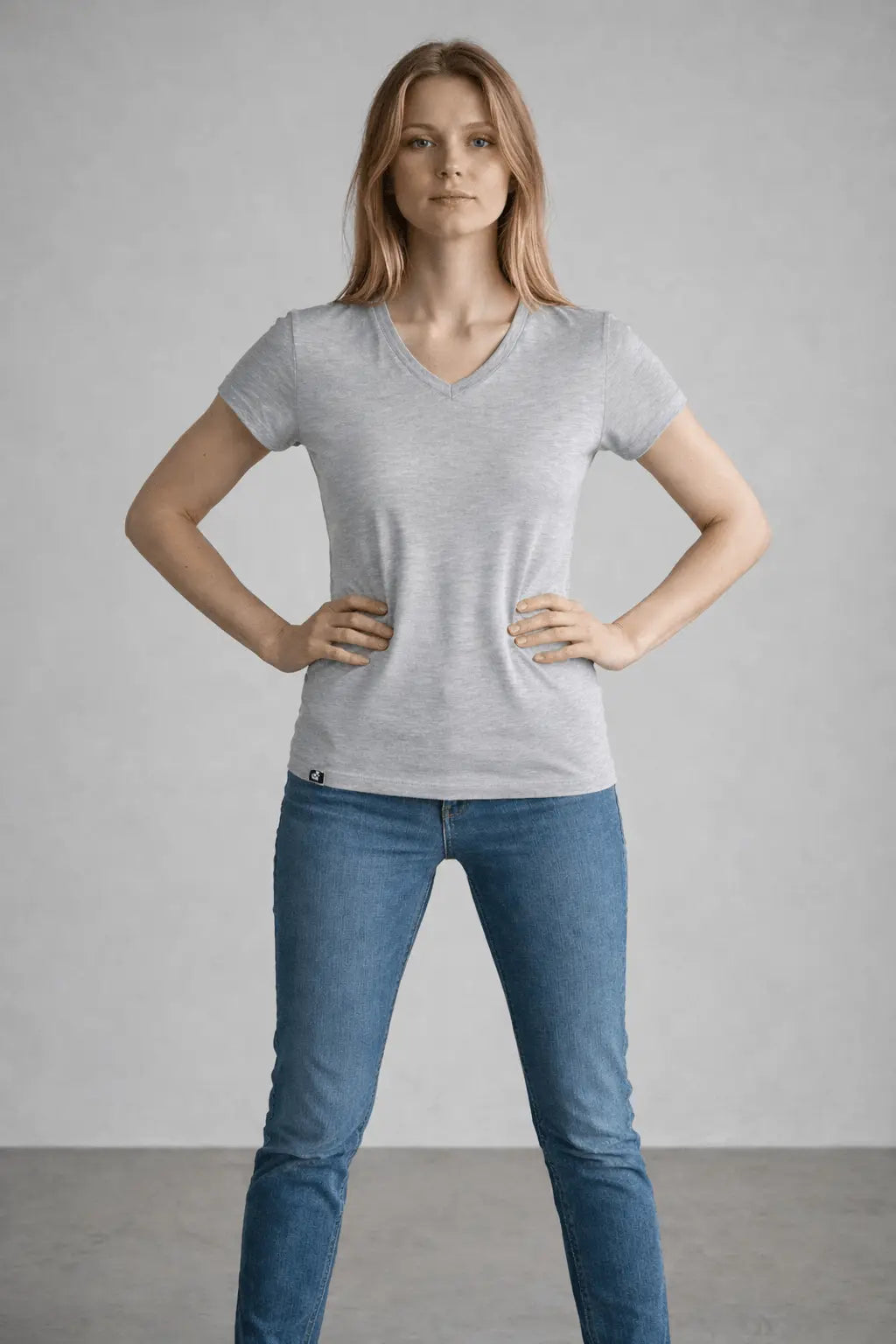Woman wearing a gray t-shirt and blue jeans against a plain background