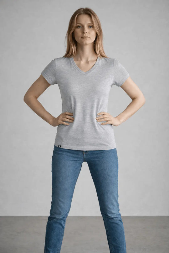Woman wearing a gray t-shirt and blue jeans against a plain background