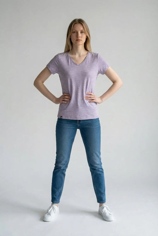 Woman wearing a light purple t-shirt and blue jeans on a plain background