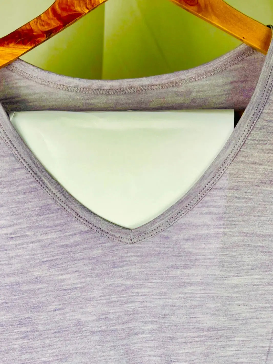 Gray tank top on a hanger with a green background