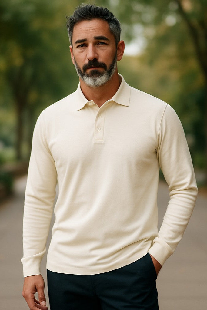 Man wearing a cream long-sleeve polo shirt standing outdoors with greenery in the background