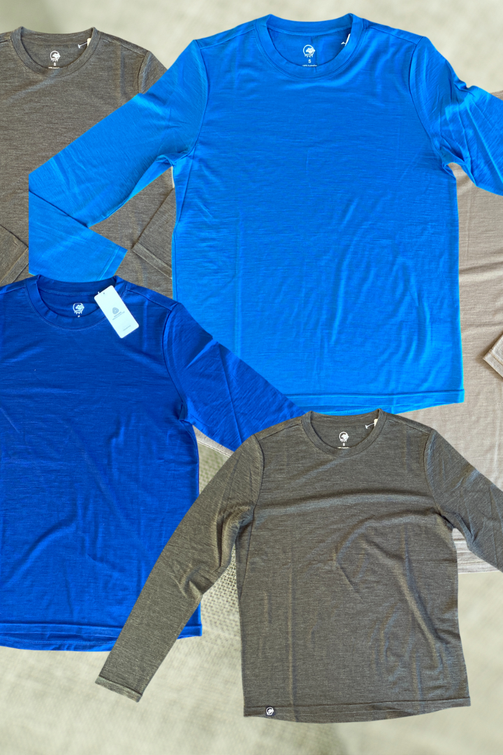 Four long-sleeve shirts in blue and gray on a textured surface