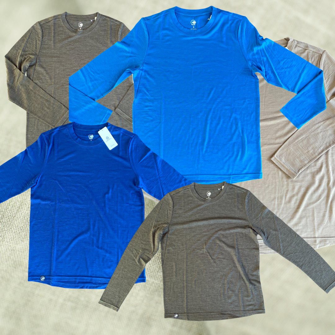 Four long-sleeve shirts in blue and gray on a textured surface