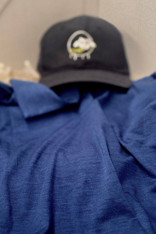 Black cap with a logo on a blue shirt against a neutral background