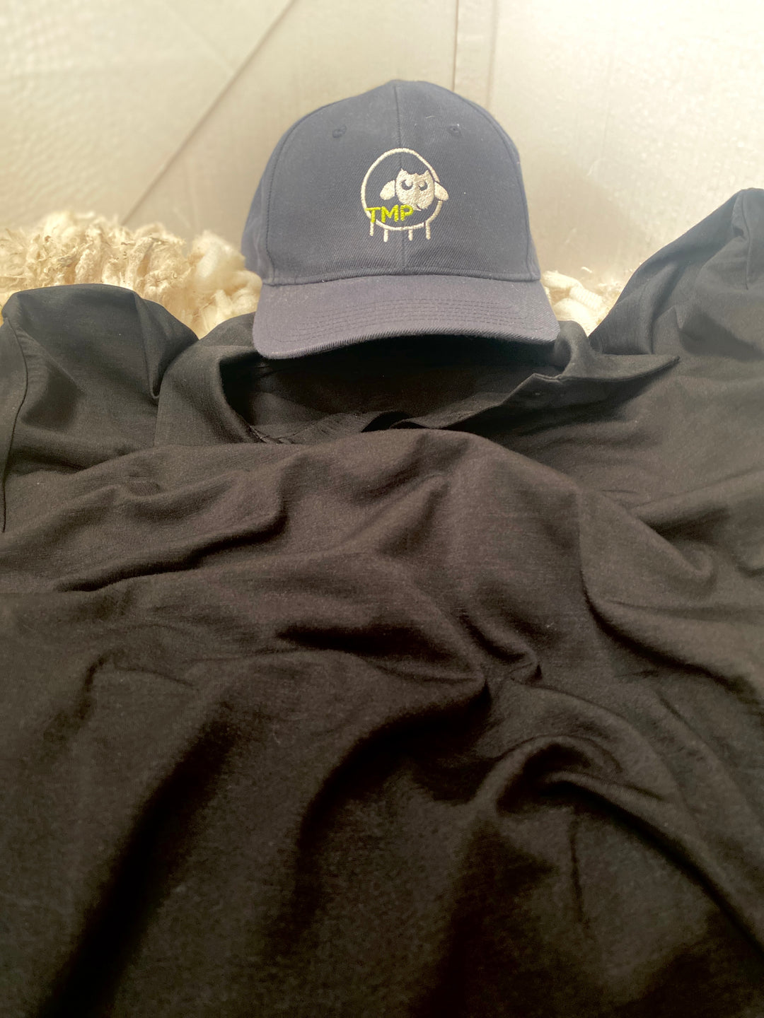 Dark gray cap with a logo on top of a dark gray hoodie