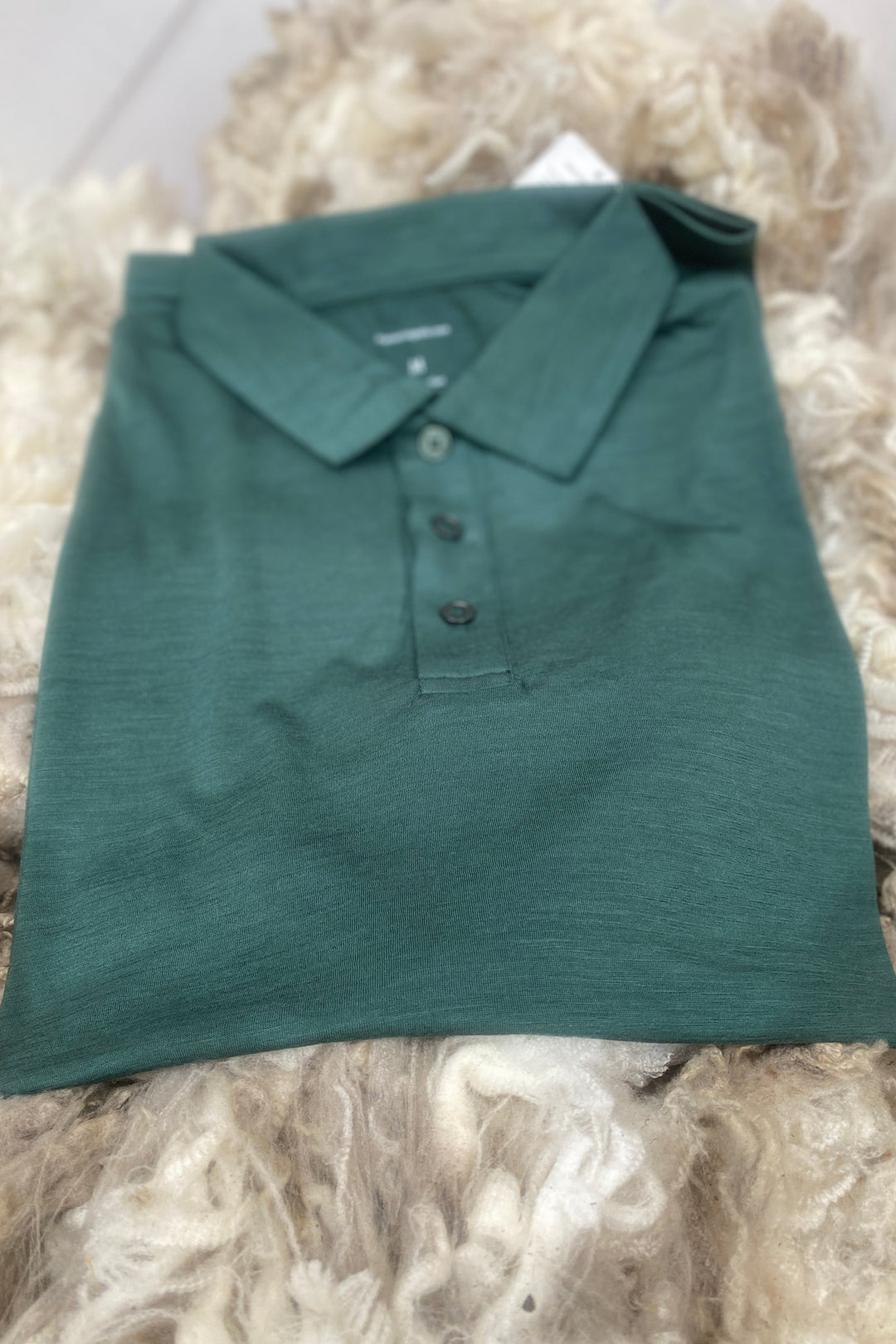 Folded green polo shirt on a textured surface