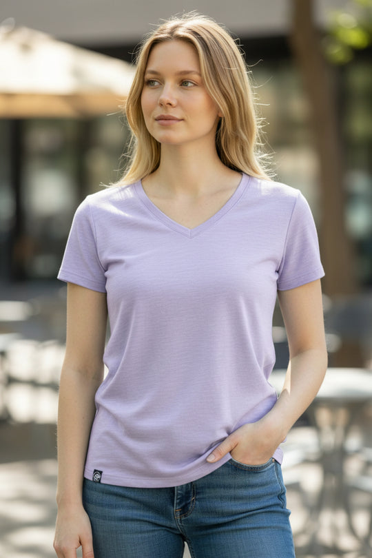 Woman wearing a light purple t-shirt and blue jeans outdoors