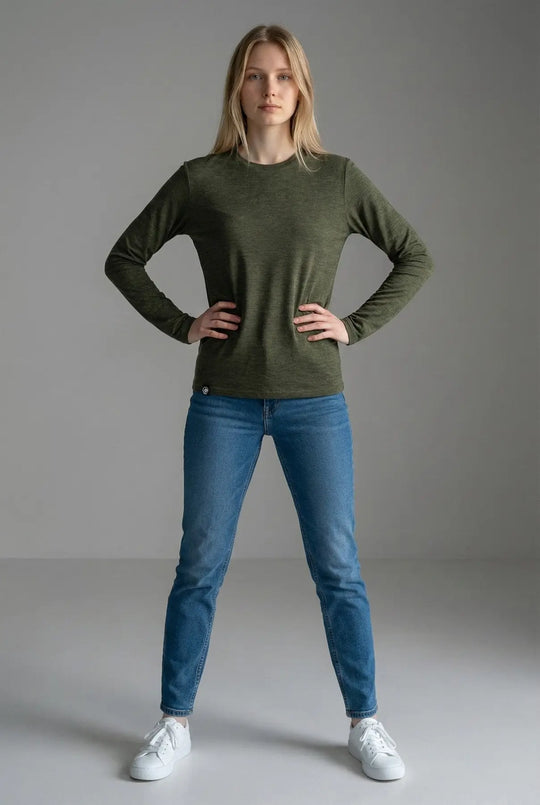 Person wearing a green long-sleeve shirt and blue jeans on a gray background