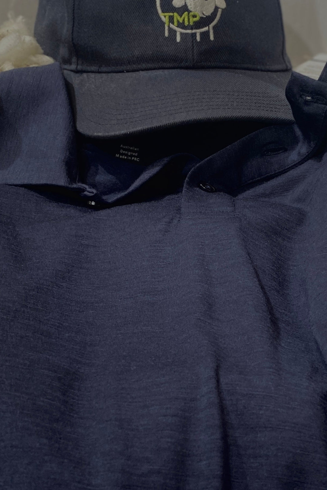 Navy blue shirt with a cap featuring a logo on a neutral background