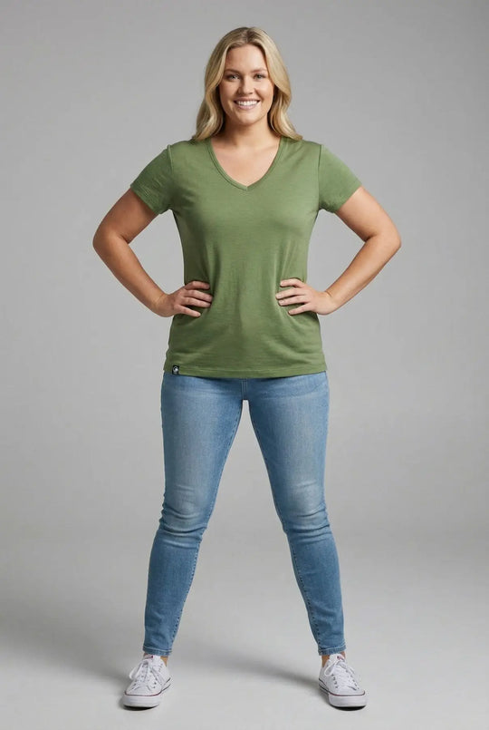 Woman wearing a green t-shirt and blue jeans on a gray background