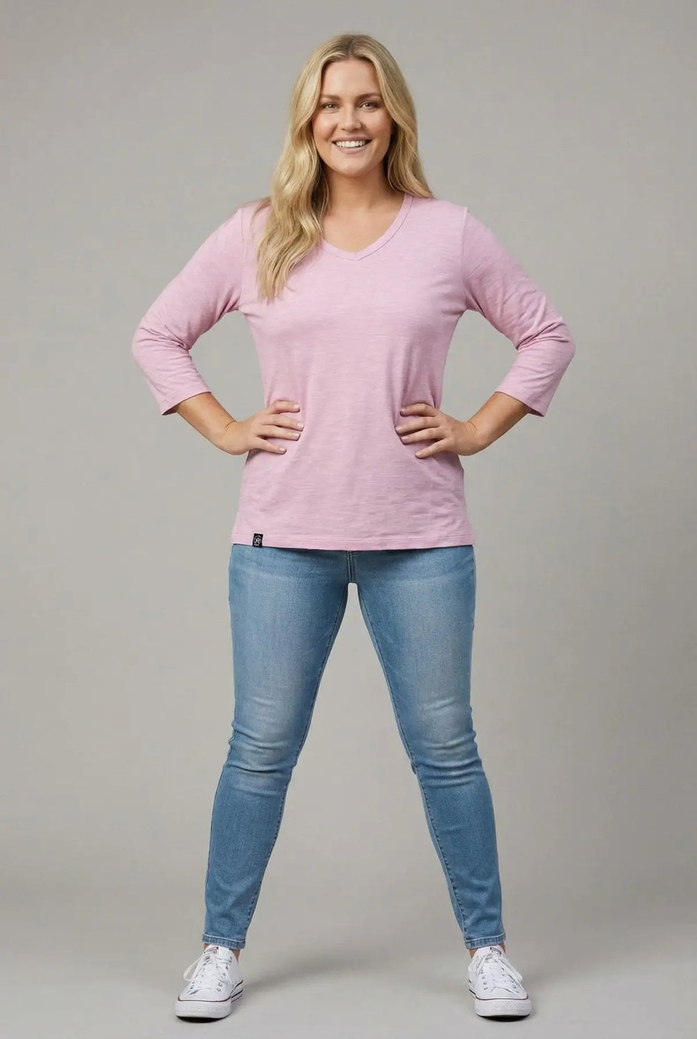 Woman wearing a pink melange 3/4 sleeve merino v-neck t-shirt and blue jeans
