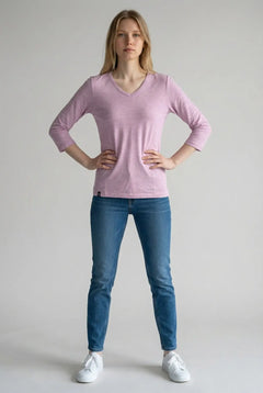 Person wearing a pink long-sleeve shirt and blue jeans on a plain background