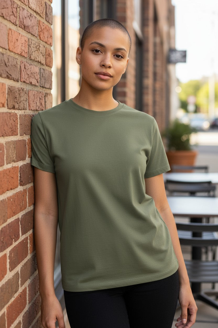 Person wearing a green t-shirt leaning against a brick wall.